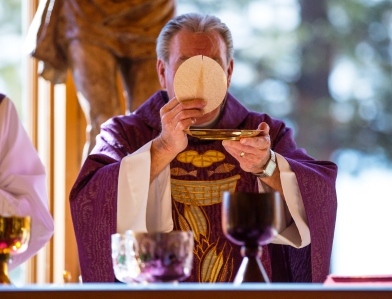 A priest, standing in the place of Jesus Christ during the one Perpetual Sacrifice of the Mass, consecrates ordinary bread and wine into the Body, Blood, Soul, and Divinity of Our Savior.